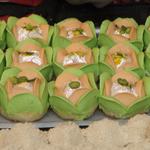 Sweets shaped like beautiful flowers with green and white petals around a center covered with silver leaf and adorned with a green pistachio nut.